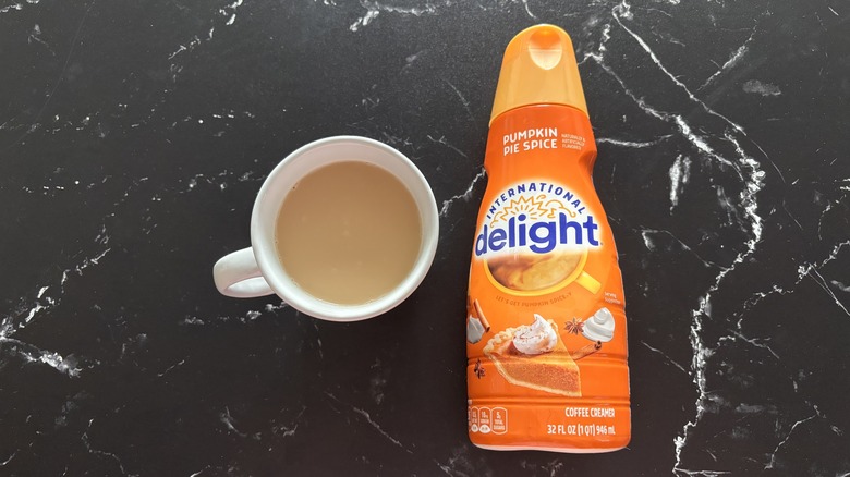 International Delight pumpkin pie spice creamer bottle next to mug of coffee