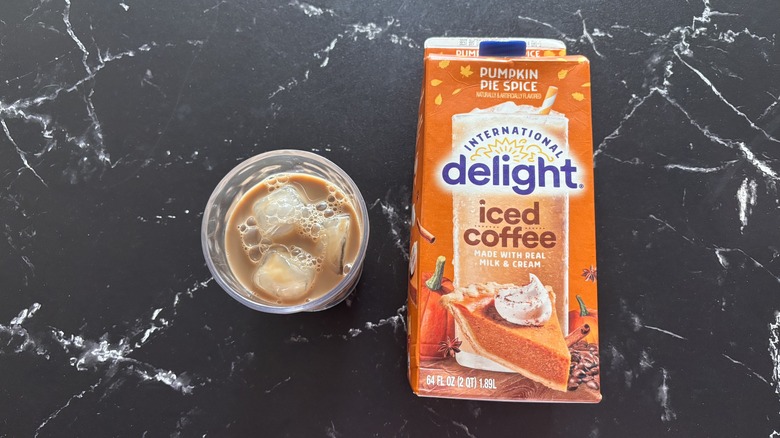 International Delight pumpkin pie spice iced coffee carton next to glass of iced coffee