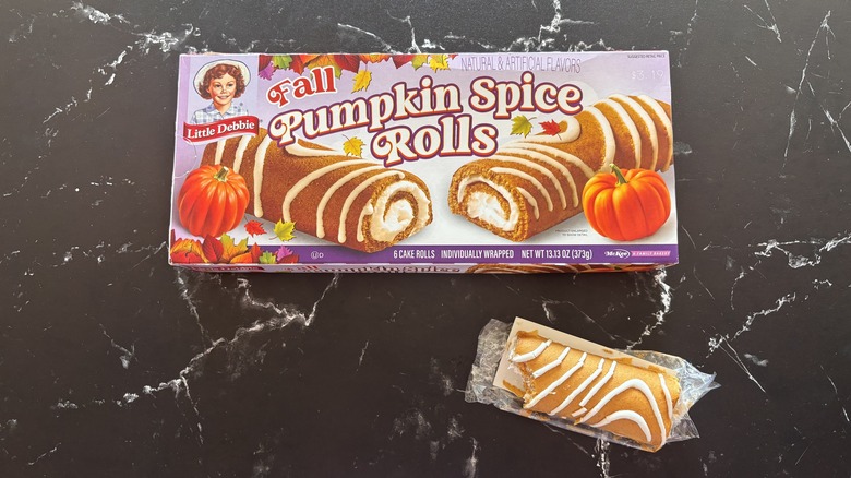 Little Debbie pumpkin spice rolls box next to pumpkin spice roll on countertop