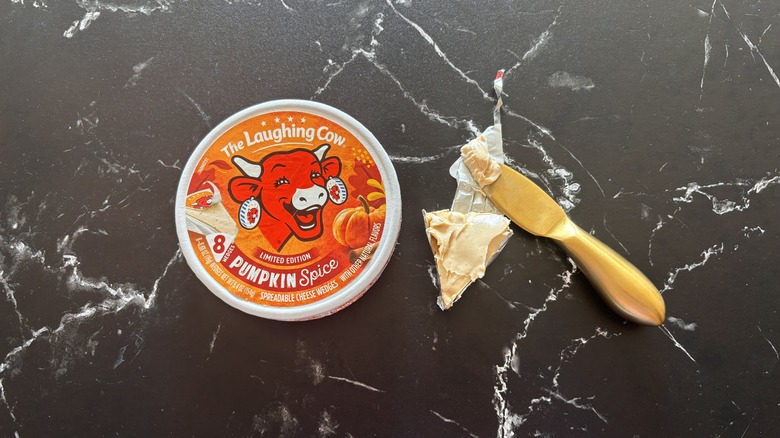 The Laughing Cow pumpkin spice cheese wedge container next to opened cheese wedge and knife