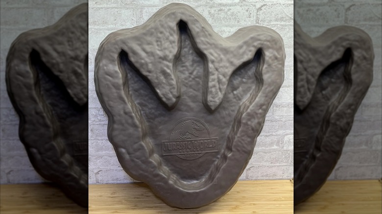 The Jurassic World Rebirth footprint bucket sits propped up on a brick wall.