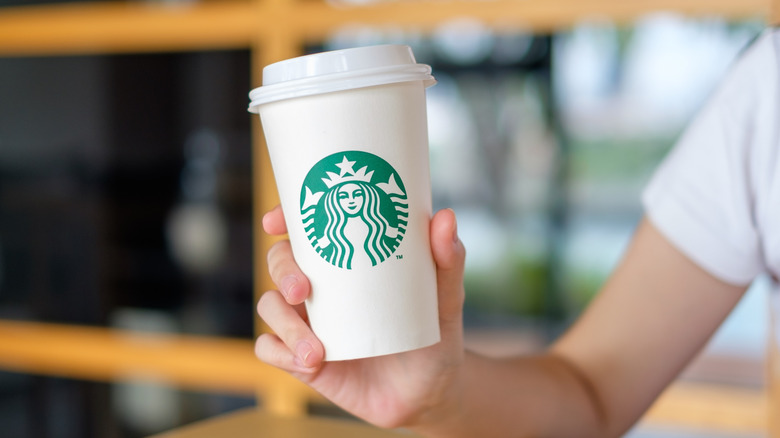 Person holding white Starbucks to-go cup
