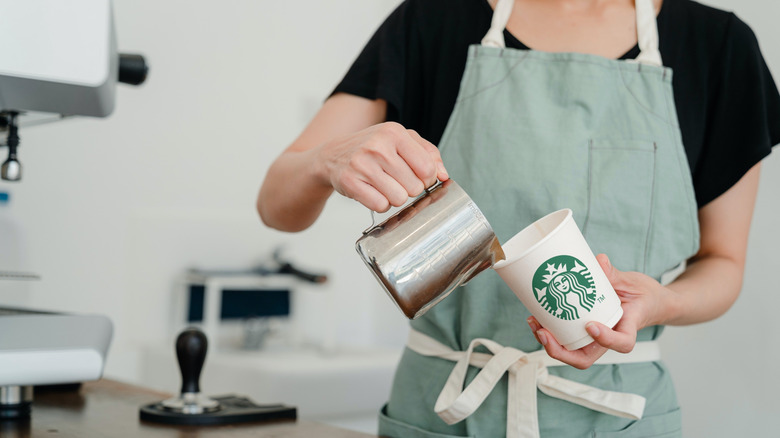 Starbucks barista pouring milk into cup