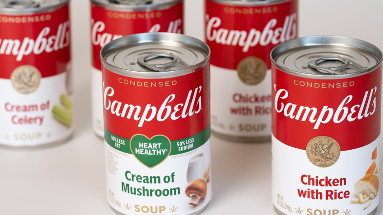 An assortment of five different Campbell's condensed soup cans on a white background