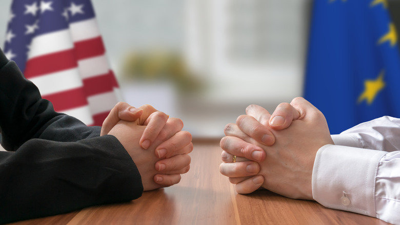 Clasped hands in front of USA and EU flags