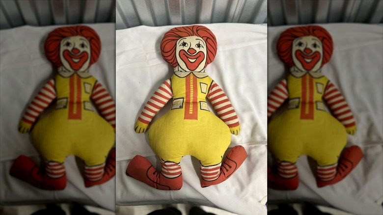 A vintage Ronald McDonald plush pillow toy sitting on a white pillow