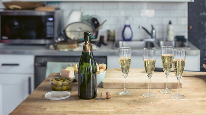 Bottle of champagne with glasses and olives with bread