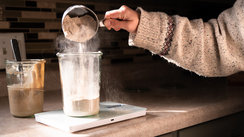 Someone feeding sourdough starter