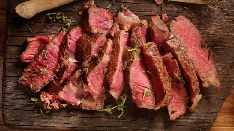 sliced rare prime rib on a rustic wood board