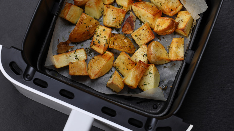 An air fryer basket full of cooked potato cubes