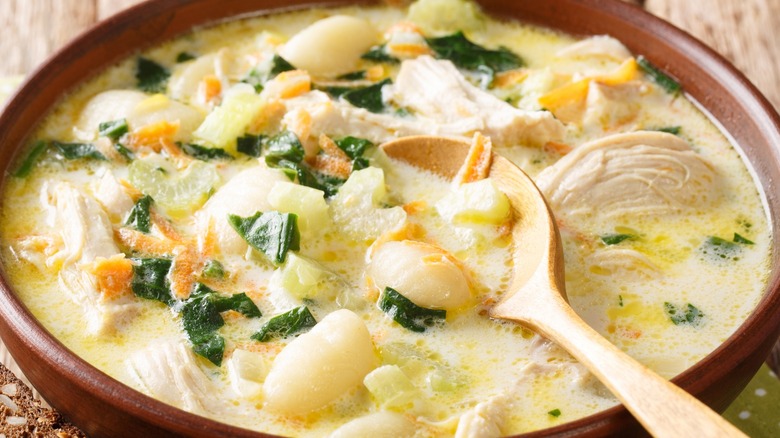 Close-up of creamy chicken and gnocchi soup with a wooden spoon