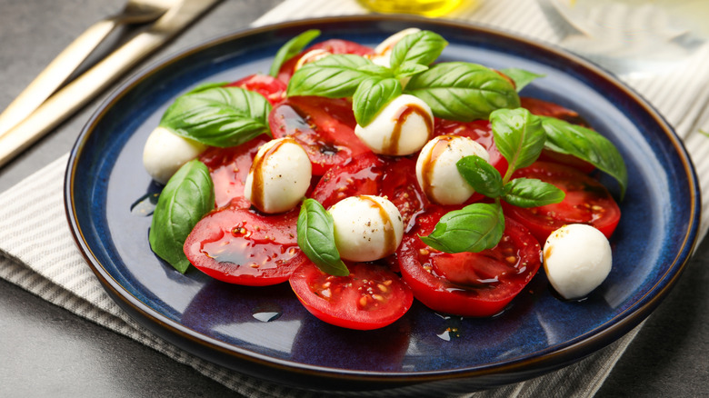 plate of sliced tomatoes with cheese and balsamic drizzle