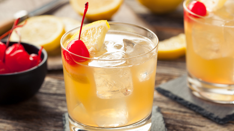 Whiskey sour cocktails with lemon and cherry garnish