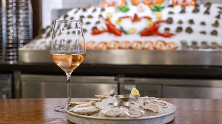 A tray of oysters and glass of wine in front of a raw bar