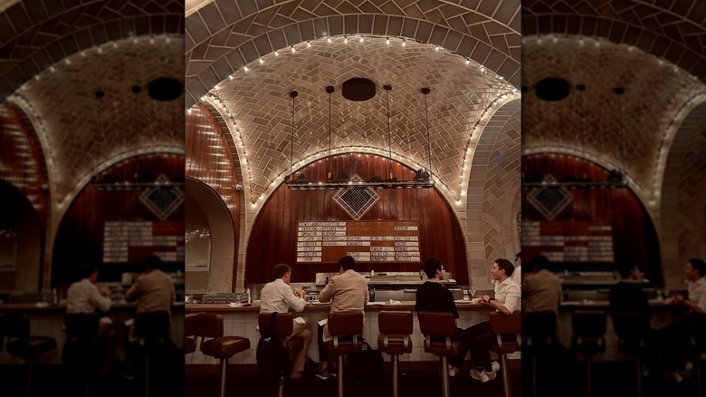 People sitting in front of a wooden-backed bar