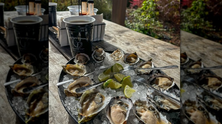 Oysters and lime on a tray of ice set on a wooden dining table