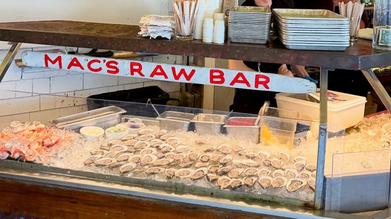 A raw bar with a red and white sign reading "Mac's Raw Bar"