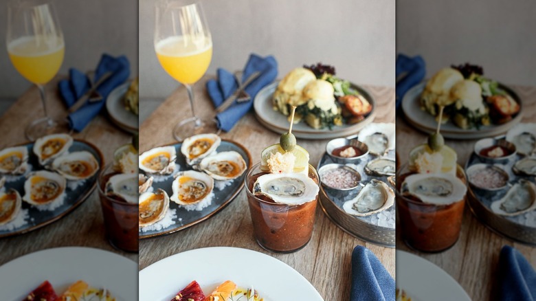An oyster on top of a bloody mary surrounded by oyster plates