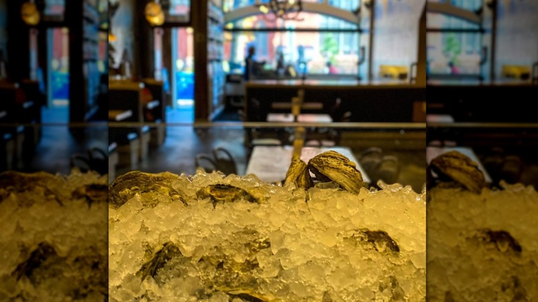A tray of ice with oysters in front of an empty restaurant