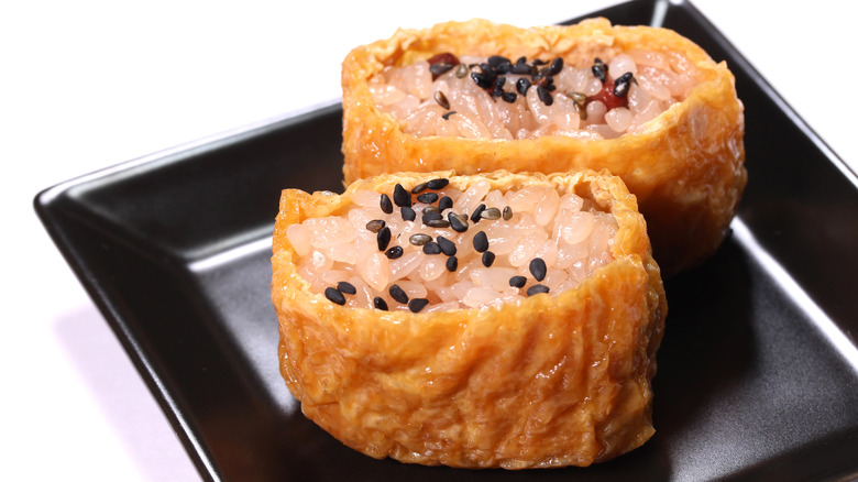 Inarizushi filled with brown rice and topped with black sesame seeds 