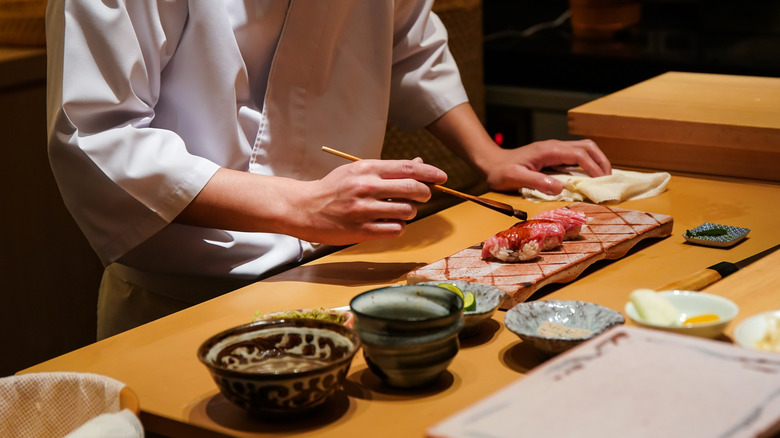 Sushi chef brushing nigiri with soy sauce
