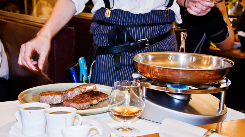 chef preparing steaks tableside in a restaurant