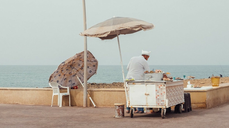 A vendor tending to his food cart by the oceanfront