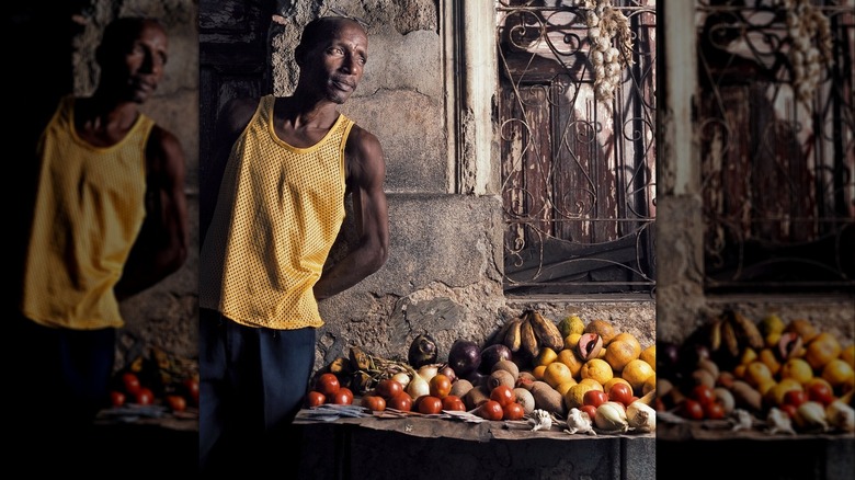 Vendor leaning against the wall next to a fruit display