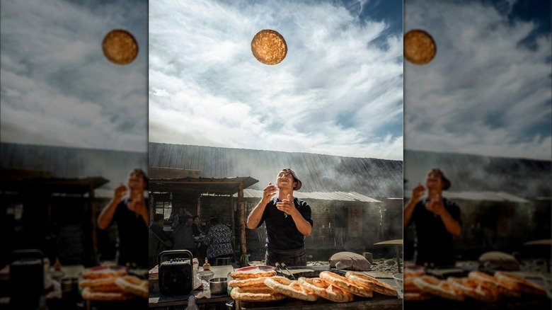 A smiling man throwing round dough in the air
