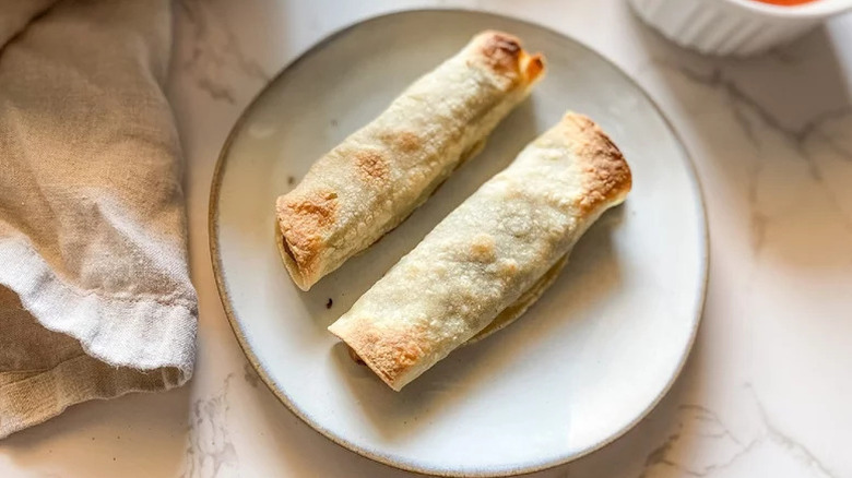 Two taquitos on beige plate