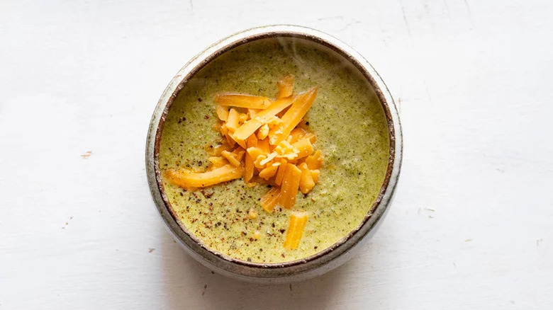 Broccoli cheddar soup in bowl on white table