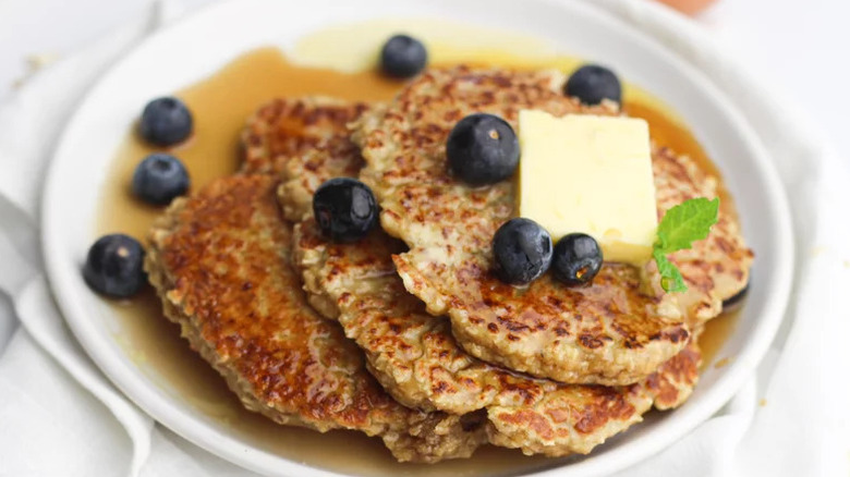 Oatmeal pancakes on white plate with blueberries and syrup