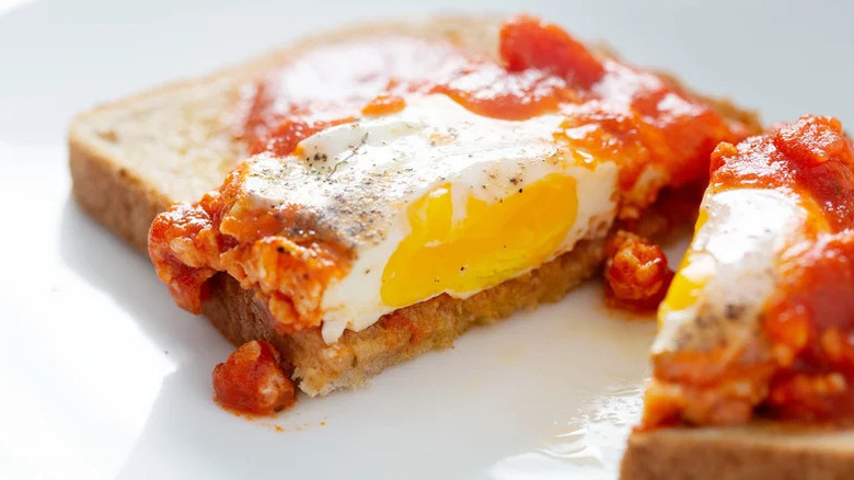 Shakshuka on slice on bread on white plate