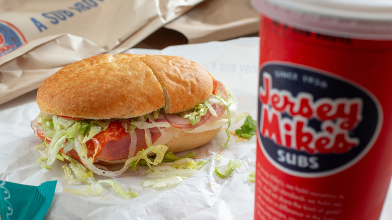Sub sandwich on wax paper sitting next to red Jersey Mike's soda cup