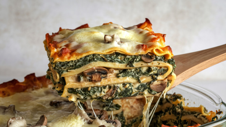 Serving a slice of spinach and mushroom lasagna