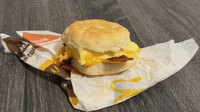a McDonald's bacon, egg, and cheese biscuit sandwich on its wrapper on a grey table