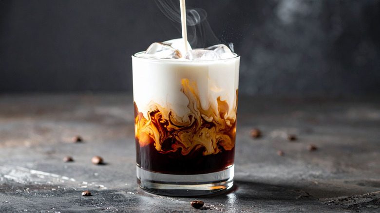 A glass of iced coffee with cold foam and a straw