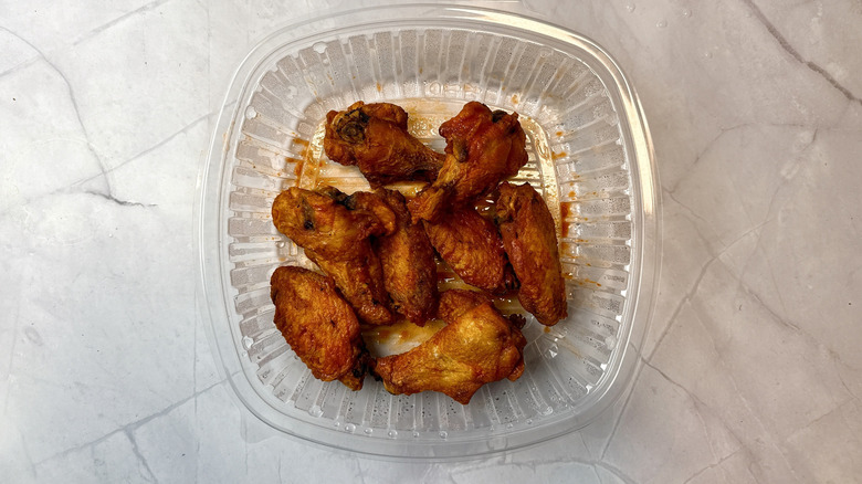 Fridays Buffalo chicken wings in a plastic takeout container
