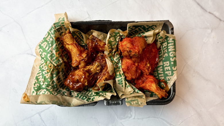 Wingstop chicken wings on paper in a plastic takeout container