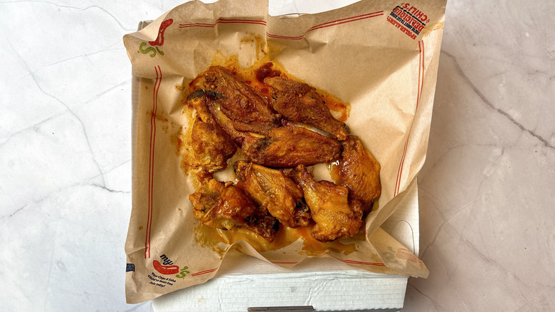 Chili's chicken wings on paper in a takeout cardboard box