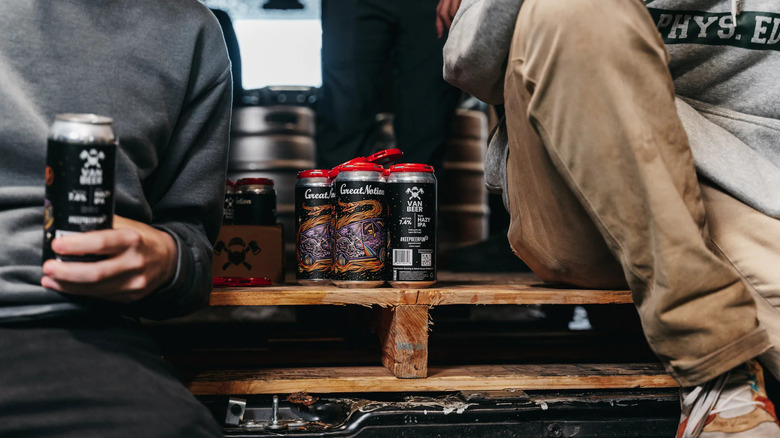 Two men sitting with four-pack of Van Beer cans