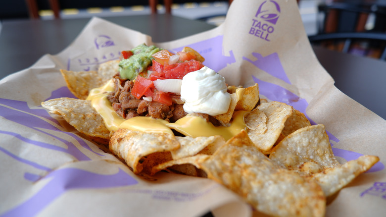 A Taco Supremes sits on a Taco Bell wrapper on a blue table