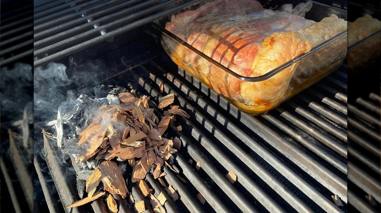 Pork belly on grill beside applewood chunks