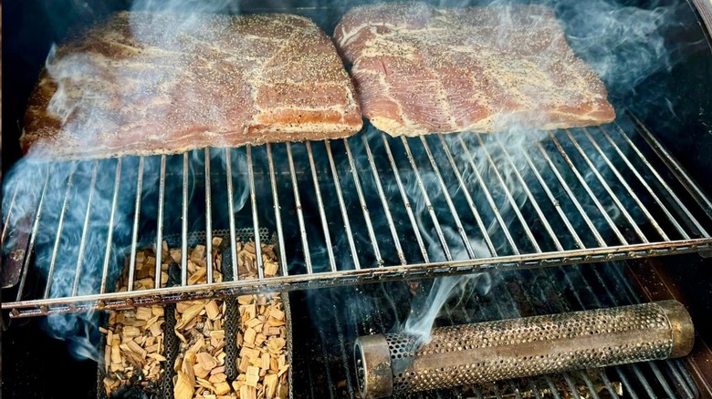 Pork belly on grill with hickory pellets beneath