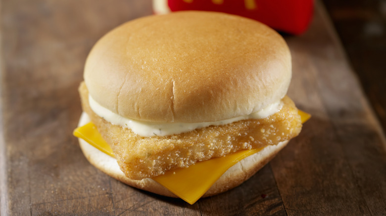 McDonald's Filet-O-Fish sandwich on a wooden table with a branded fry container in the background