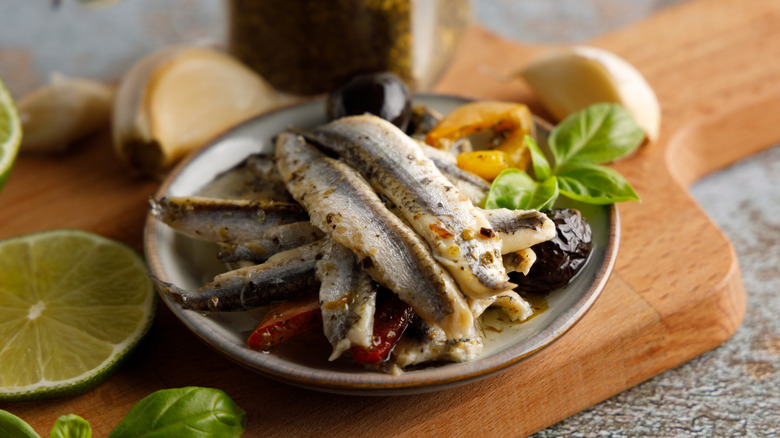 anchovy filets on a plate with aromatics surrounding