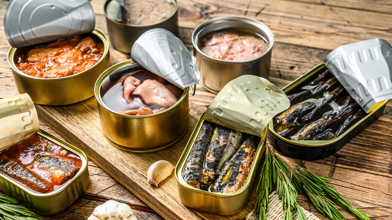 a variety of opened tinned fish containers on wooden board