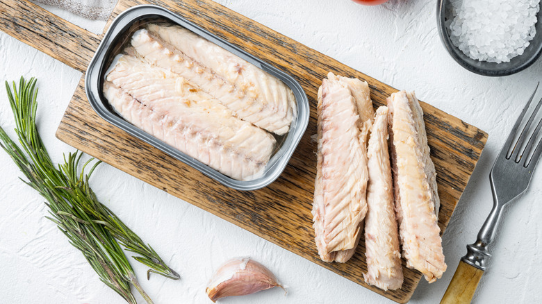 an opened tin of mackerel on a wooden board