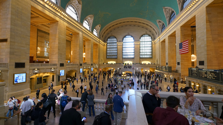 Three people sit at a corner table of Cipriani Dolci, overlooking the main train hall