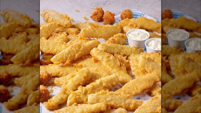Captain D's Batter Dipped Fish sticks displayed on paper wrapper next to cups of tartar sauce and hush puppies